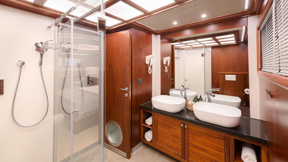 Badezimmer mit Dusche, Doppelwaschbecken, Spiegel und Holzschränken in der Master Kabine der Lady Gita.